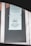 A printed notice taped to a window, indicating a preference for debit or credit card payments over cash. The sign includes a graphic of a hand holding a card. Another message is posted above, possibly policy or informational text.
