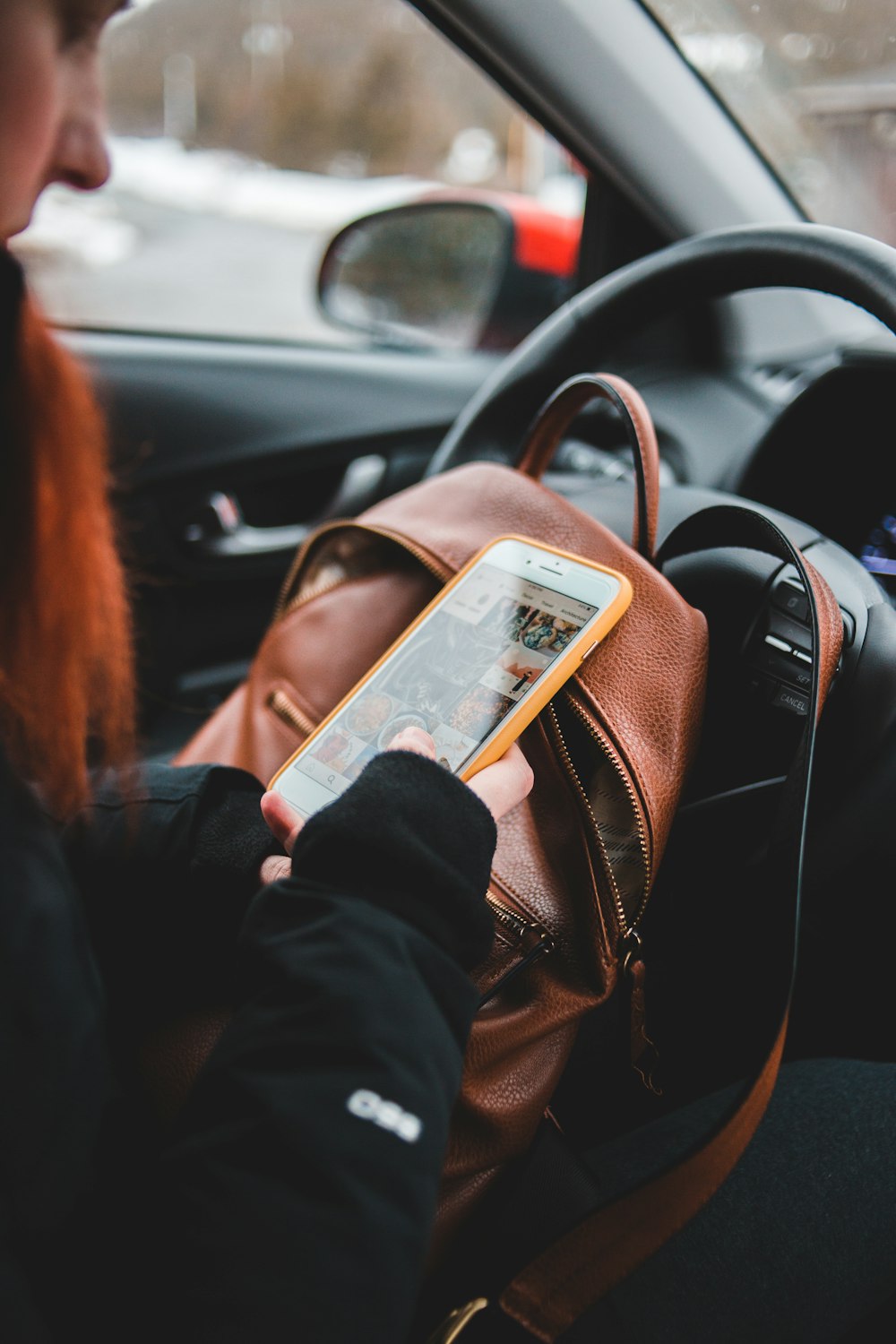 Mujer en chaqueta negra sosteniendo iPhone 6 plateado