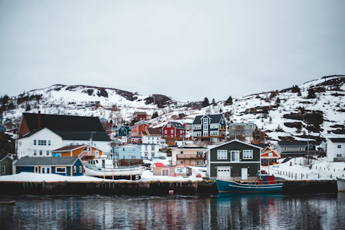 A minimalist Scandinavian coastal village with muted tones and calm waters under a cloudy sky.