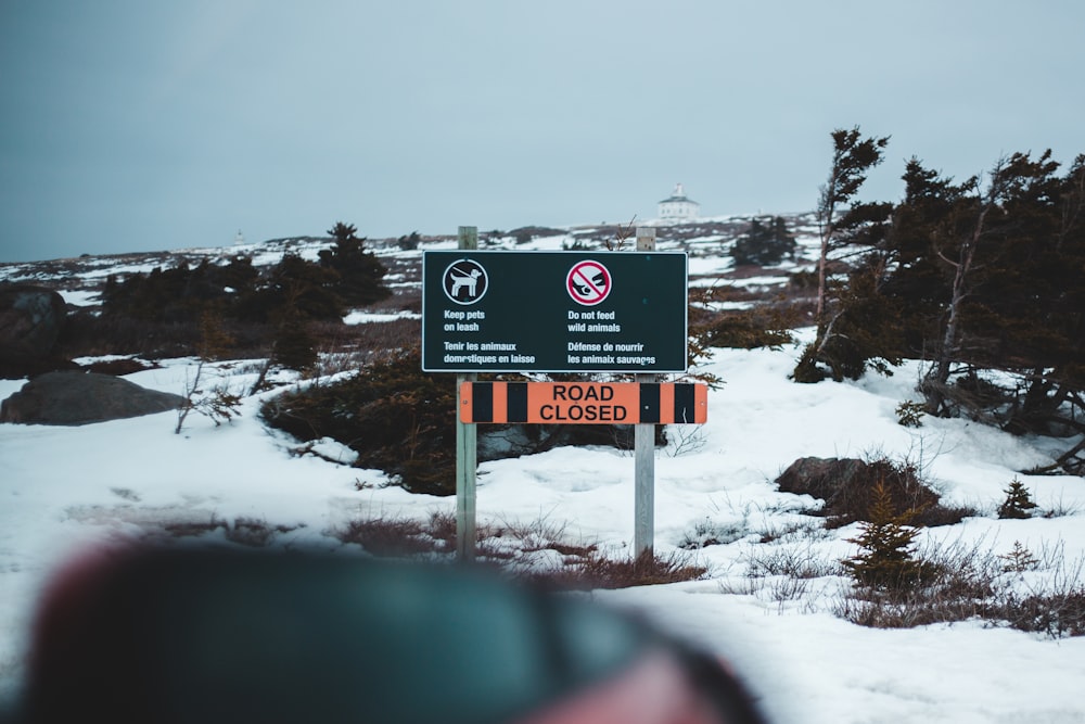 black and white wooden signage on snow covered ground