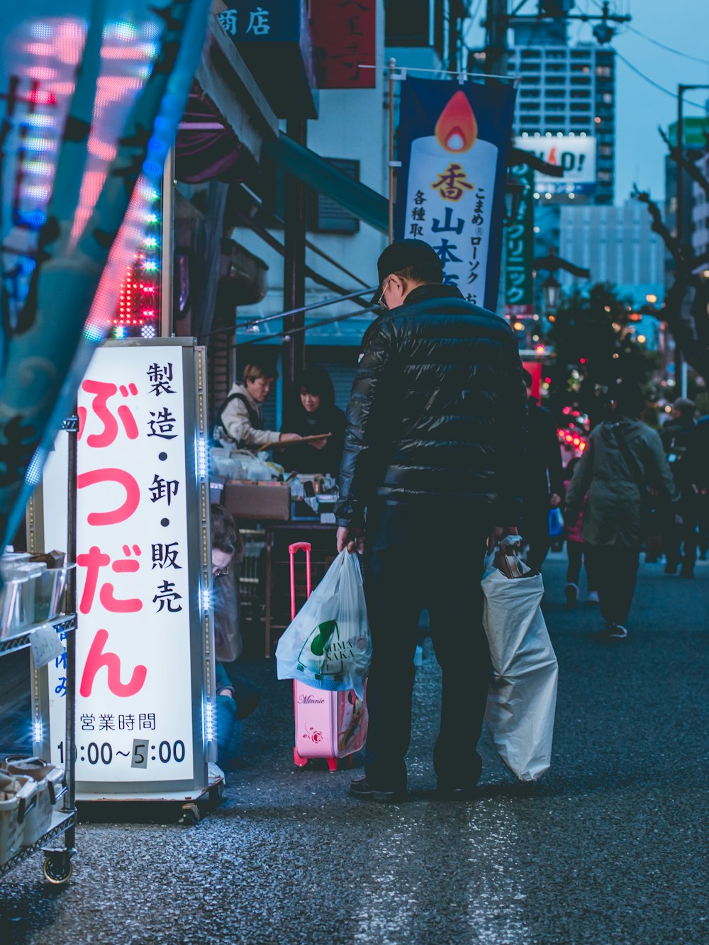 man in black jacket and blue denim jeans walking on street during daytime