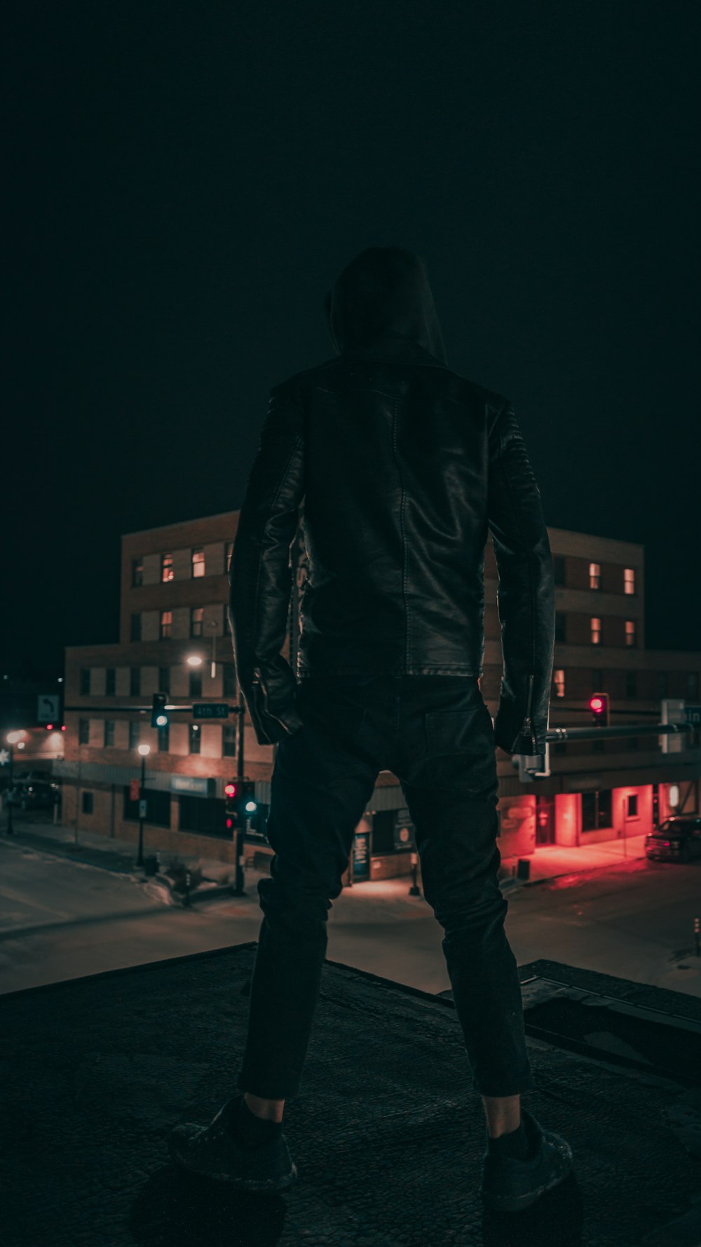 hombre con chaqueta de cuero negro de pie en la calle durante la noche