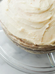 Close-up of a homemade cake with creamy frosting and delicate decorations on a rustic wooden table.