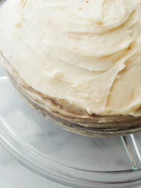 Close-up of a beautifully decorated homemade chocolate cake with creamy frosting on a rustic wooden table.