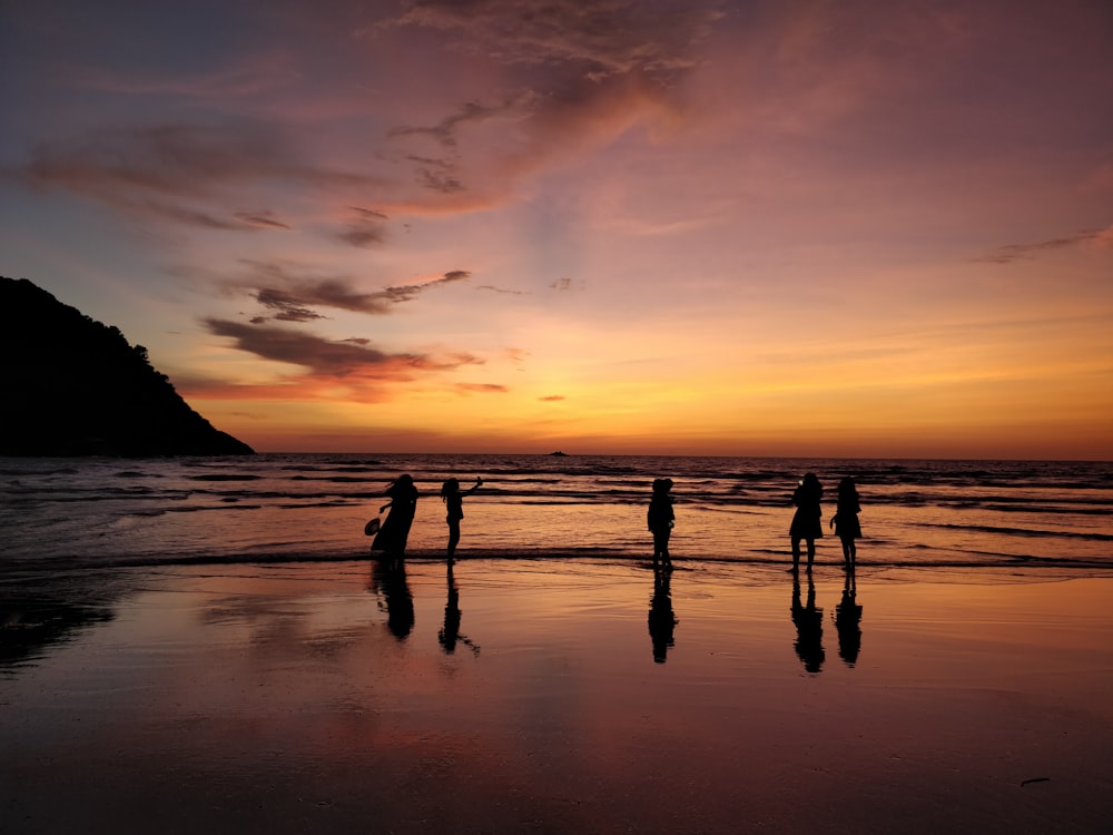 Silhouette von Menschen am Strand während des Sonnenuntergangs