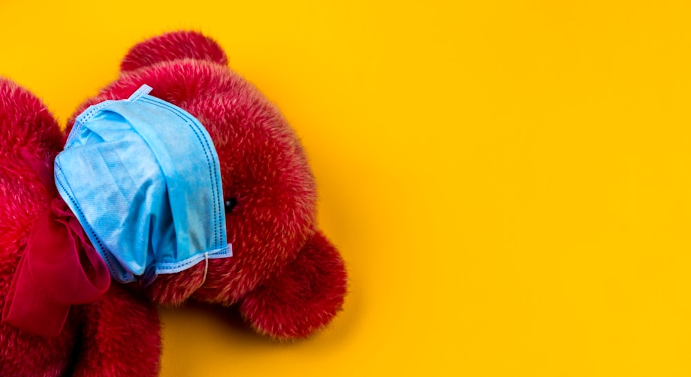 Juguete de peluche de oso rojo sobre superficie amarilla