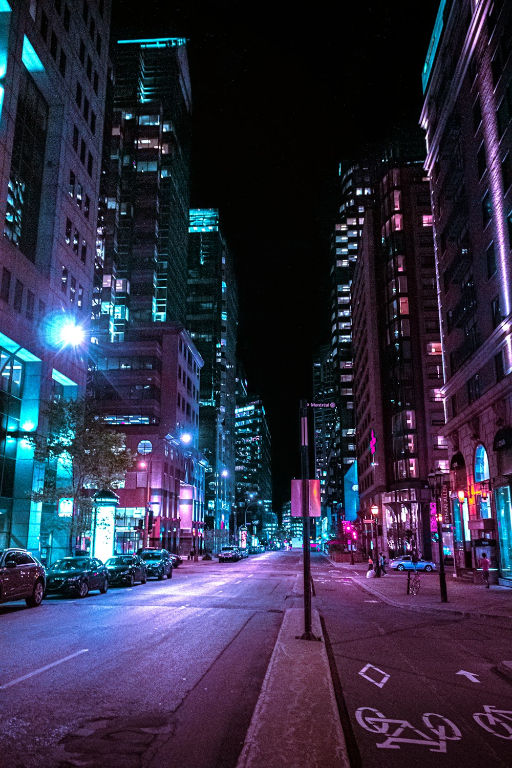 cars on road between high rise buildings during night time