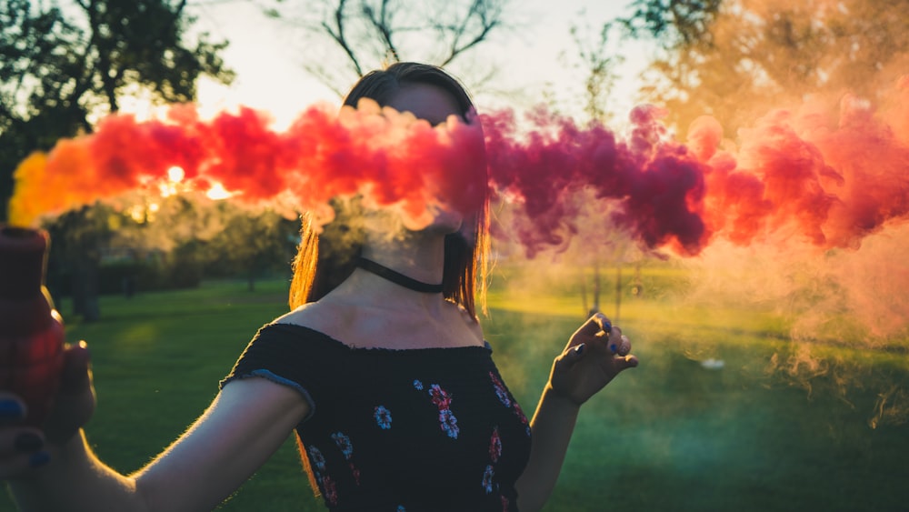 woman in black and white floral dress holding pink smoke