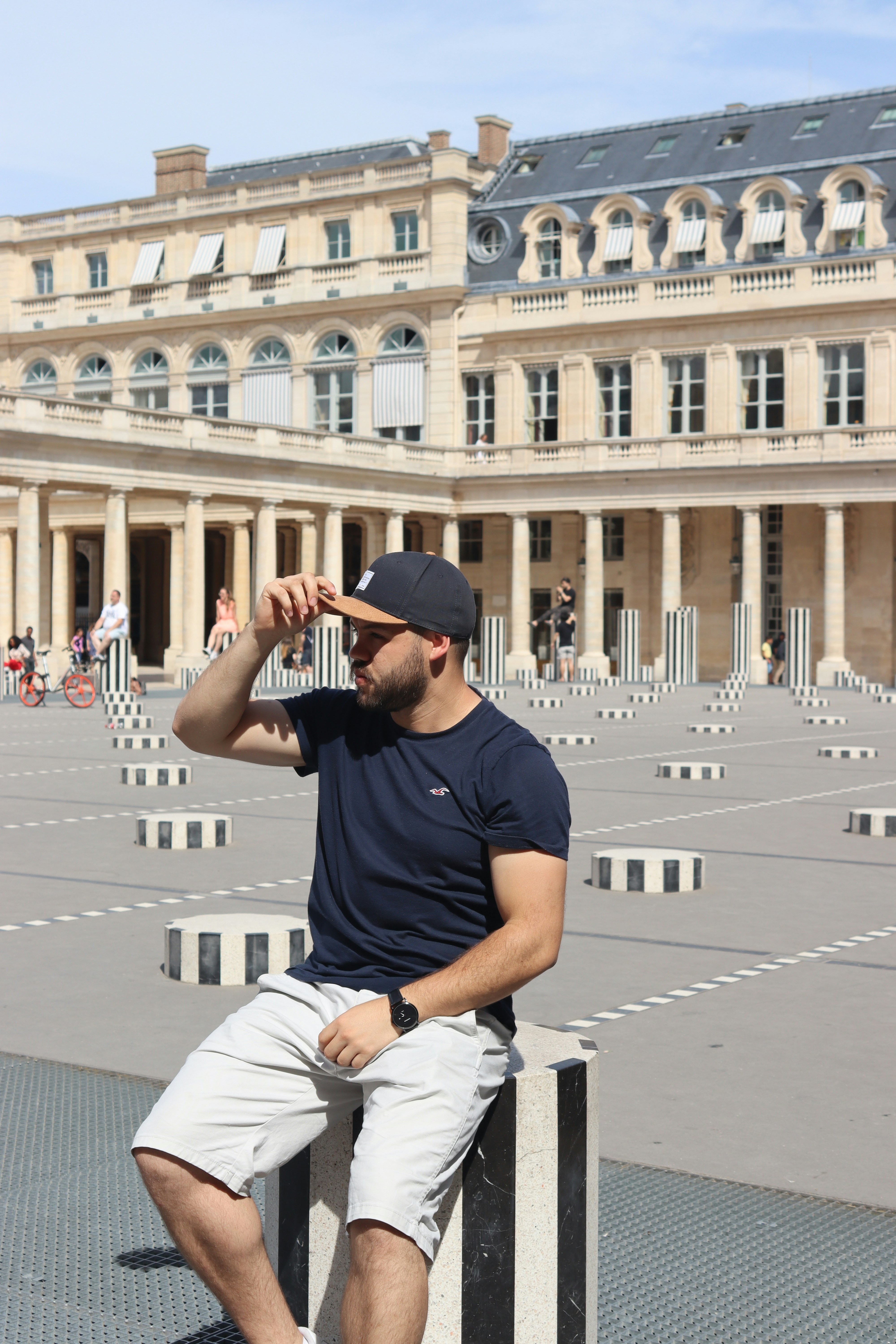 man in black crew neck t-shirt and white pants sitting on white concrete bench during