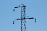 Close-up of silicone polymer insulators installed on high-voltage power lines against a clear blue sky.