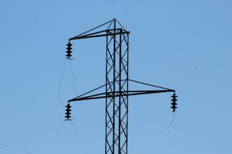 Close-up of porcelain electrical insulators installed on high-voltage power lines against a clear blue sky.