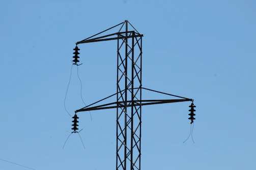 Close-up of silicone polymer insulators installed on high-voltage power lines against a clear blue sky.