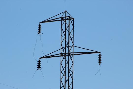 Close-up of porcelain electrical insulators installed on high-voltage power lines against a clear blue sky.