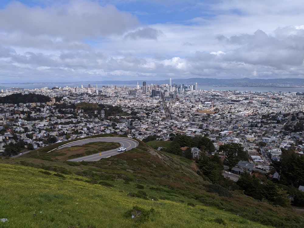 city buildings on green grass field under white clouds and blue sky during daytime