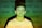 A young person stands against a background filled with various words like 'angry,' 'powerful,' and 'sexist' projected onto them. The lighting casts a green and yellowish hue across the scene, creating a contrast with the person's white shirt.