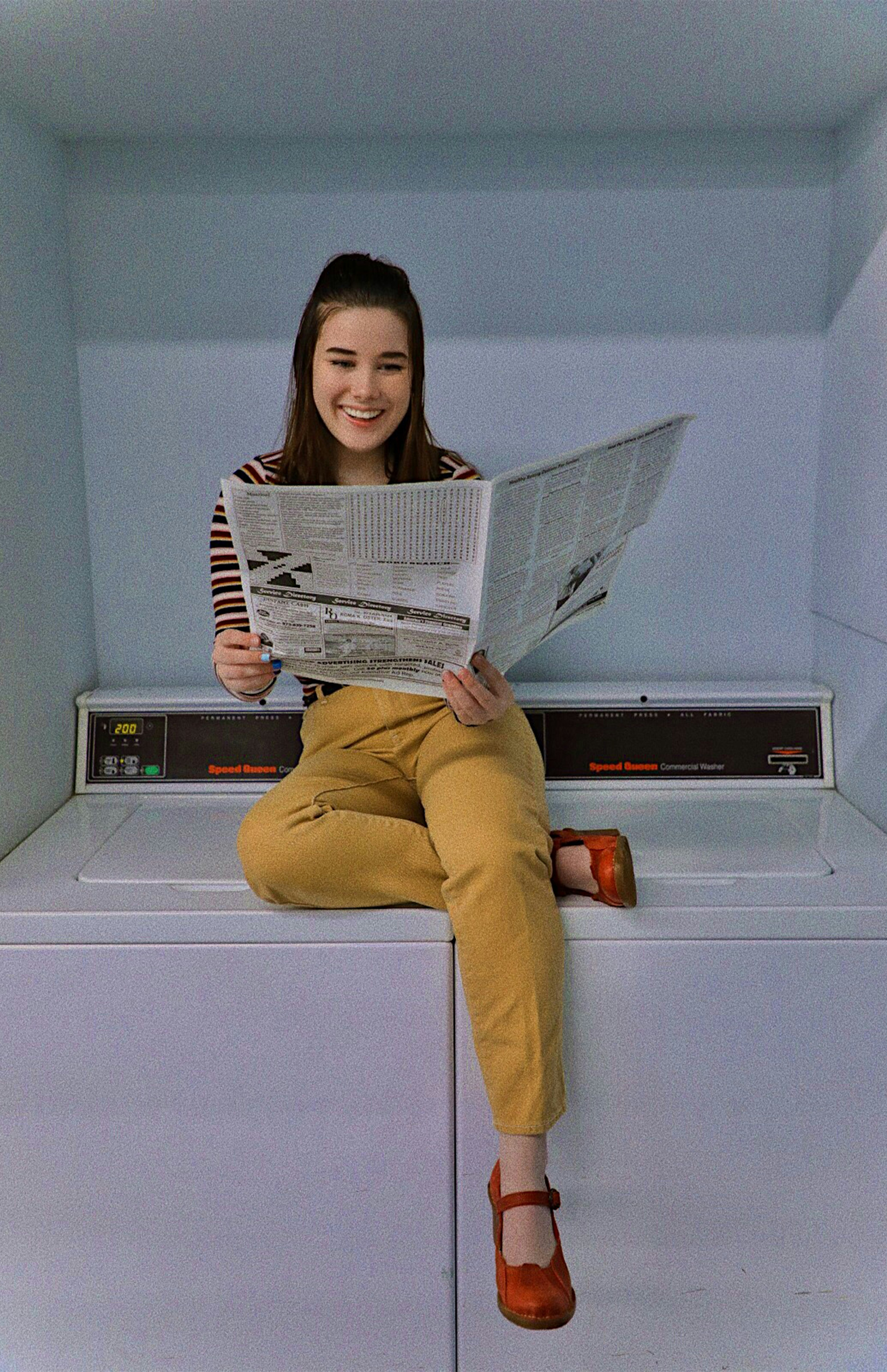 woman in yellow pants holding newspaper