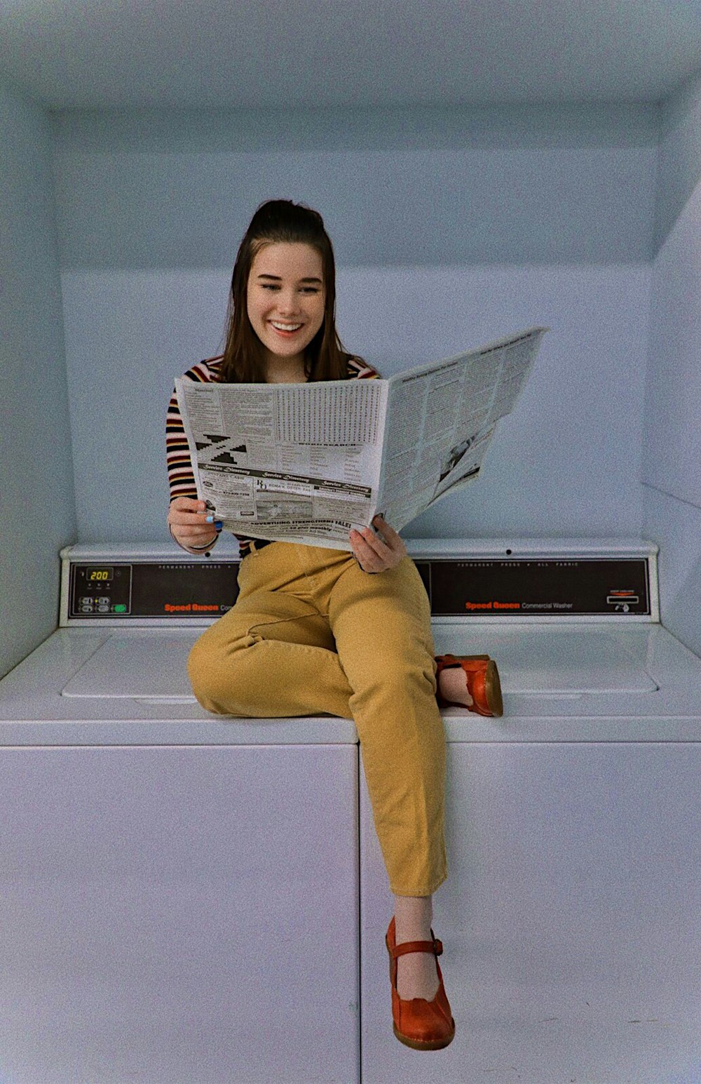 woman in yellow pants holding newspaper