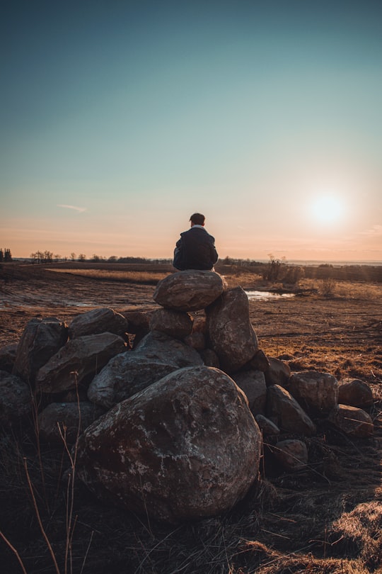 man sitting on rock formation during sunset in King City Canada