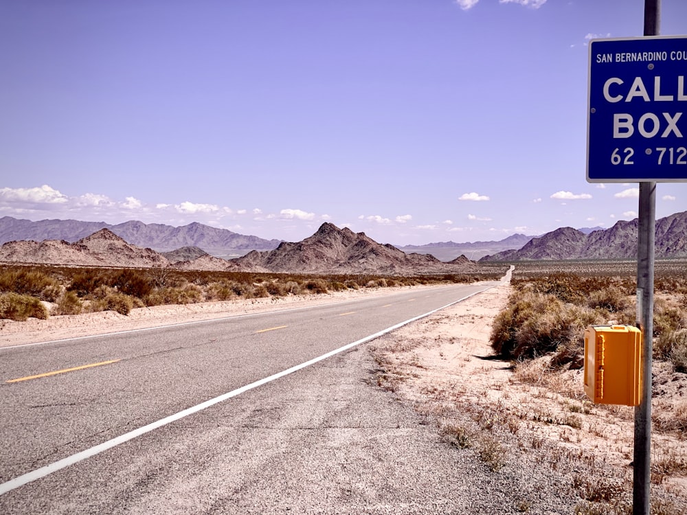 gray concrete road near brown mountain under blue sky during daytime