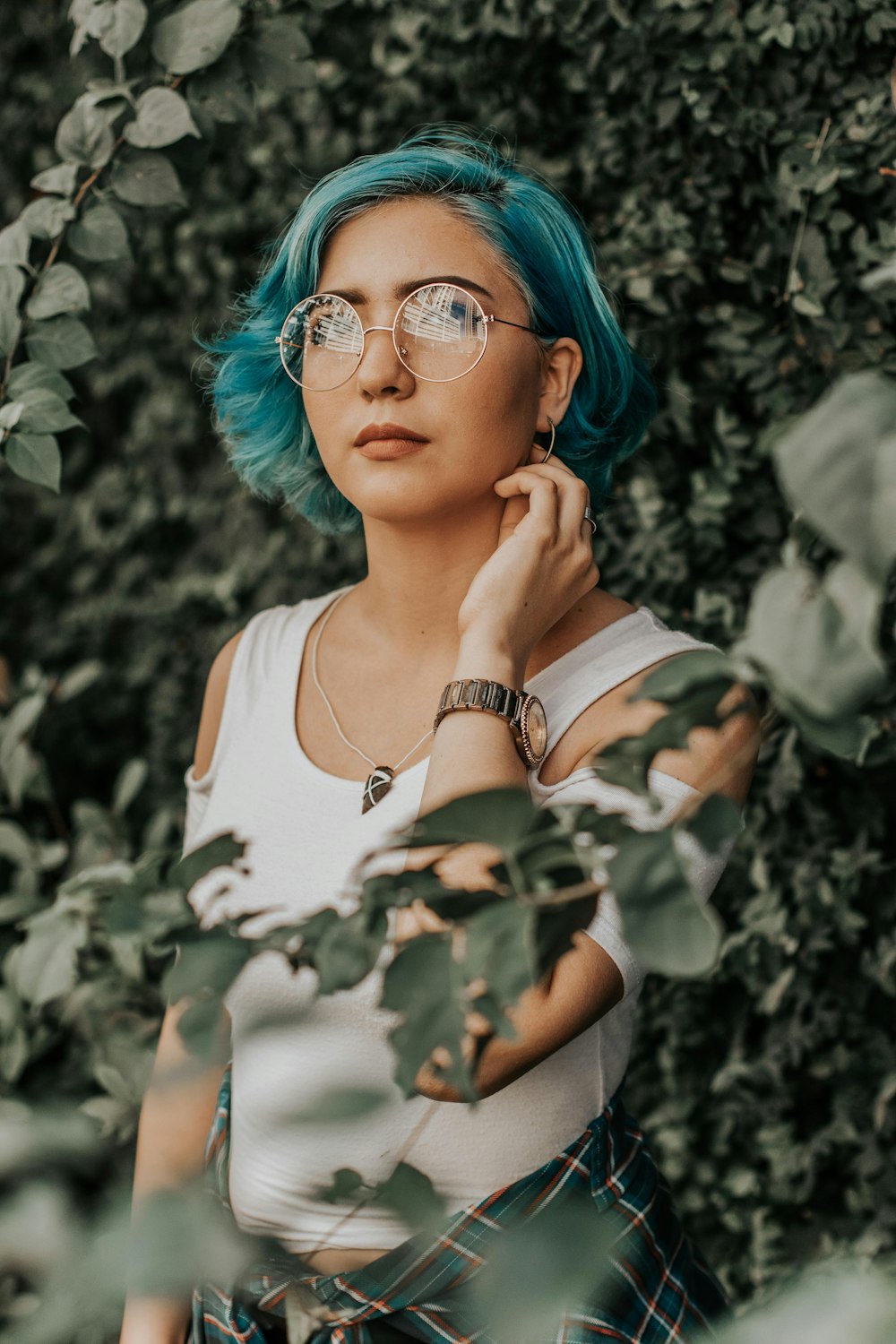 Mujer con camisa de camuflaje blanca y verde con gafas de montura azul