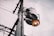 A utility pole with an attached transformer and an industrial-style streetlight. The sky is overcast, providing a muted backdrop. Electrical wires extend outward, creating a network across the scene.
