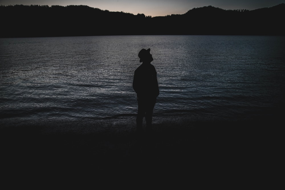 silhouette of man standing on seashore during night time