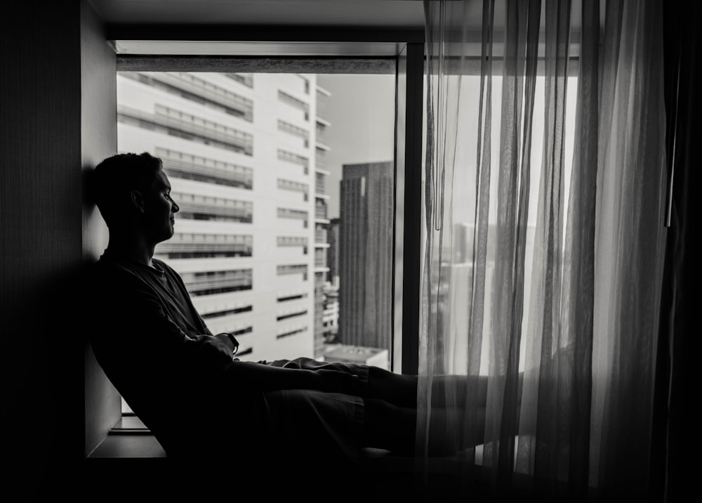 man in black jacket sitting beside window