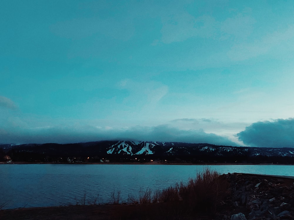 body of water near mountain under blue sky during daytime