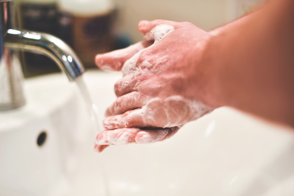 person washing hands on sink
