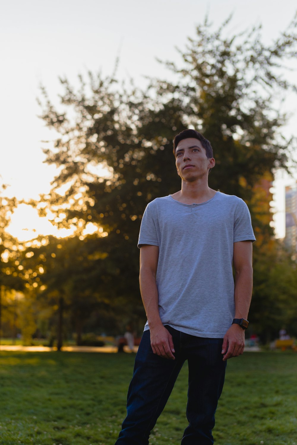 man in white crew neck t-shirt standing near green trees during daytime