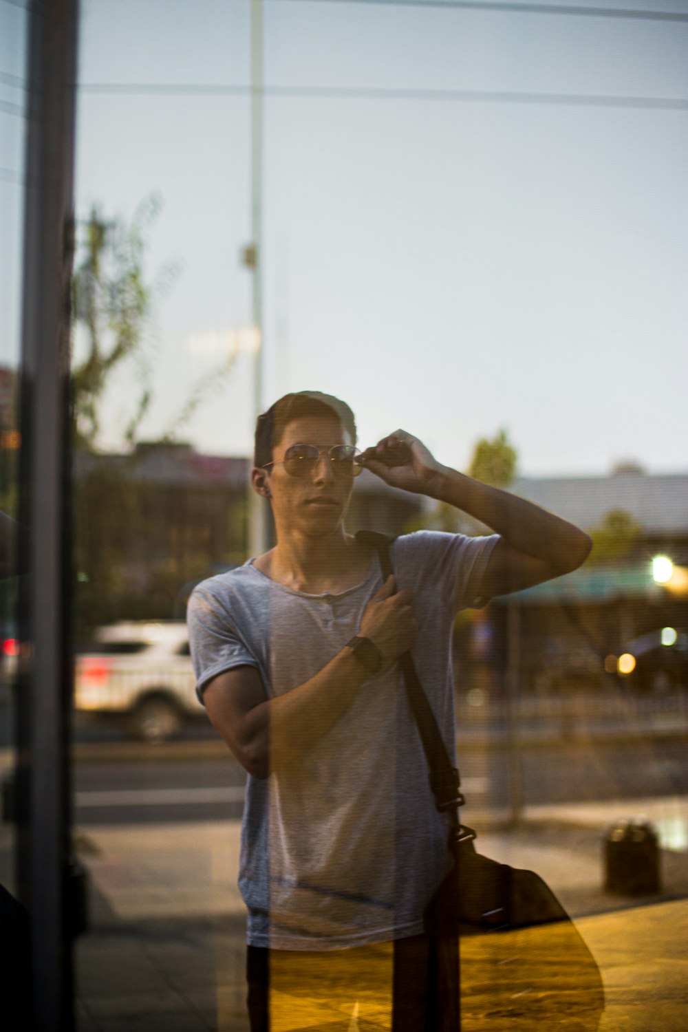 man in gray crew neck t-shirt standing near glass window during daytime