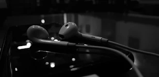 A pair of Lumina Apparel earphones resting on a wooden table beside a softly glowing lamp.