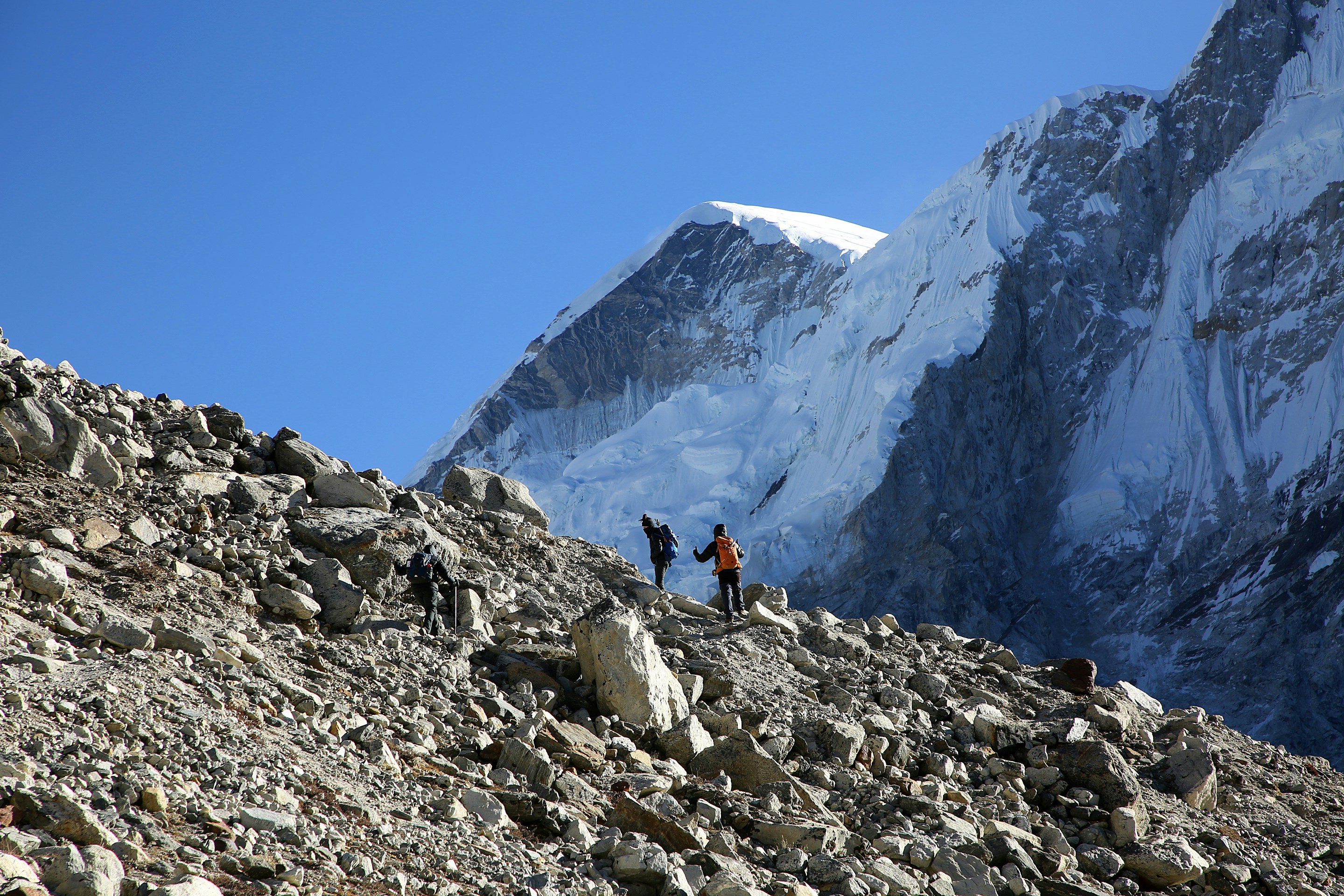 person in black jacket and black pants standing on rocky mountain during daytime