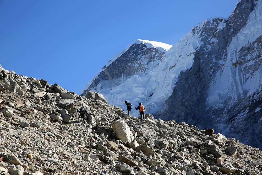 person in black jacket and black pants standing on rocky mountain during daytime