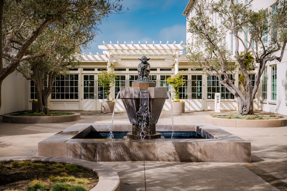 black outdoor fountain in front of white concrete building during daytime