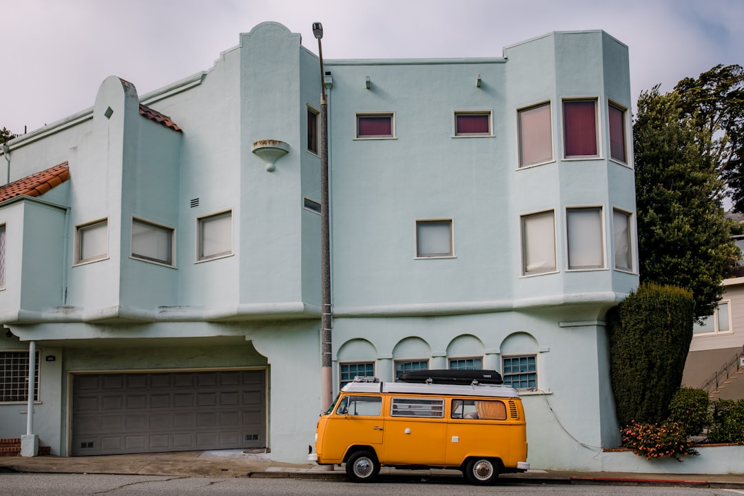 yellow and black van parked beside white concrete building during daytime