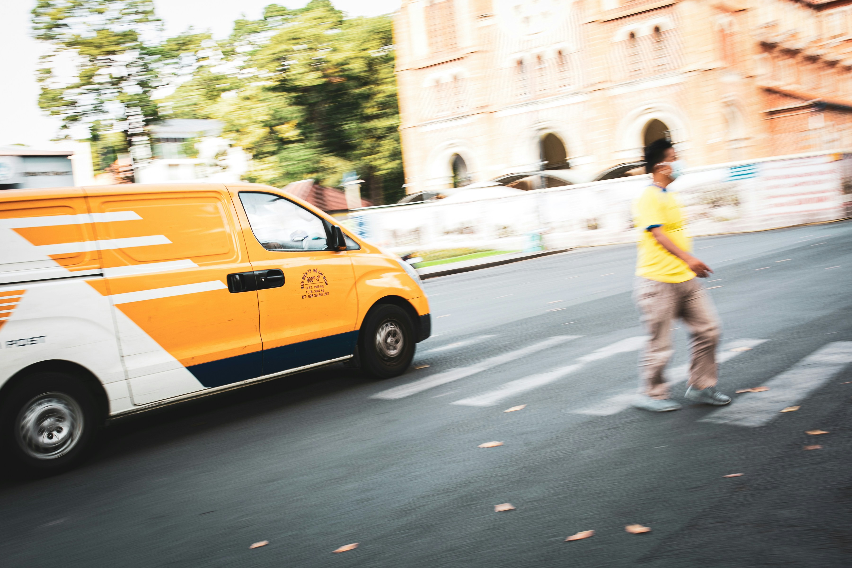 man in yellow shirt and blue shorts standing on pedestrian lane during daytime