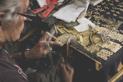 An elderly Colombian artisan carefully crafting a motorcycle accessory by hand.