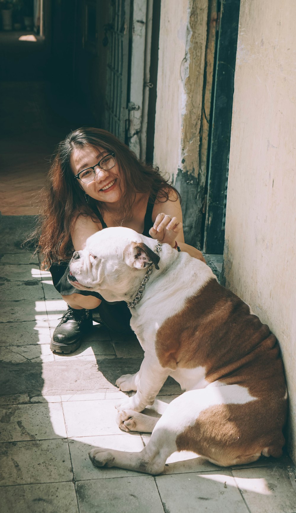 woman in black leather jacket hugging white and brown short coated dog