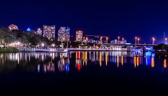 city skyline across body of water during night time