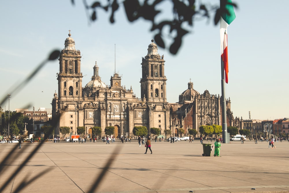 Personas caminando por la acera cerca de un edificio de hormigón marrón durante el día