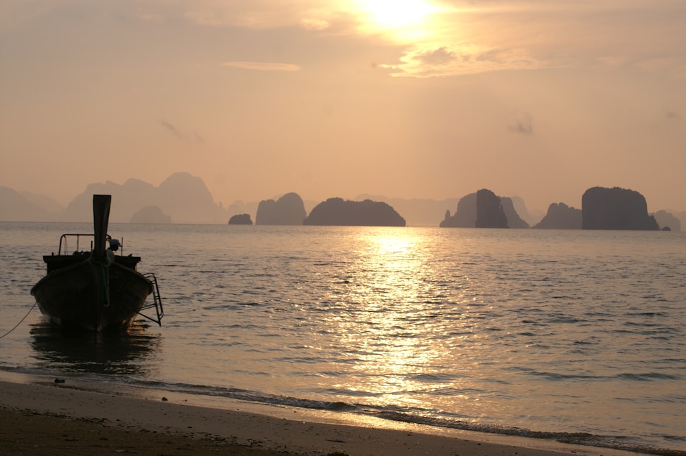 silhouette of boat on sea during sunset