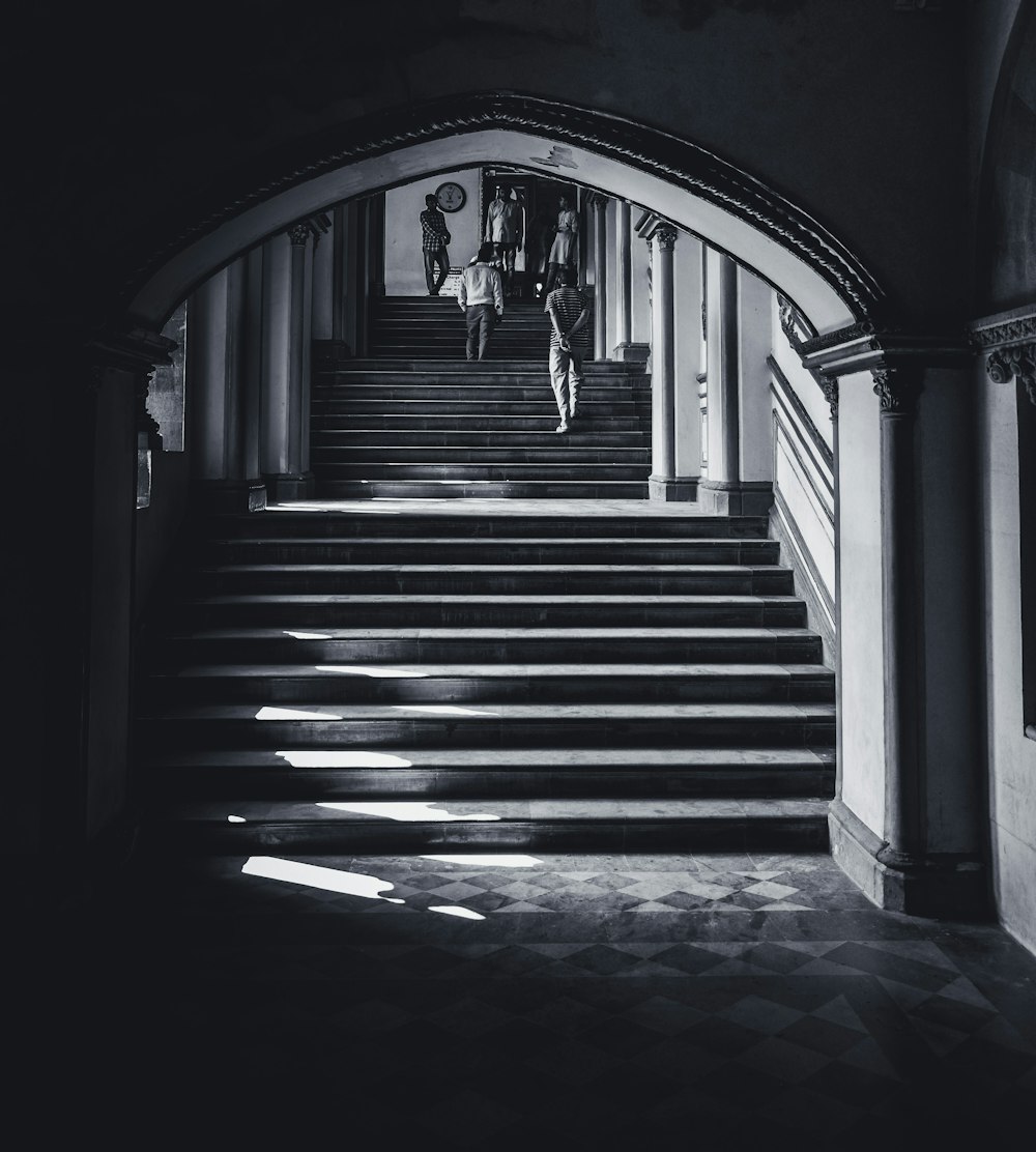 grayscale photo of person walking on stairs