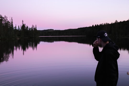 man in black jacket holding fishing rod near lake during daytime in Røa Norway