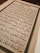 An open book with text written in Arabic script, featuring ornate calligraphy. The page is framed by an elaborate border and the content is aligned in clear rows across the page.