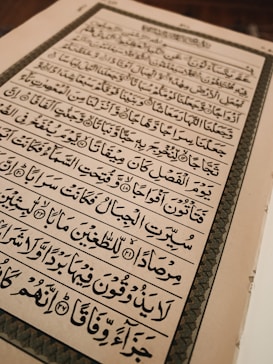 An open book with text written in Arabic script, featuring ornate calligraphy. The page is framed by an elaborate border and the content is aligned in clear rows across the page.