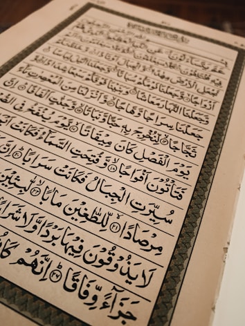 An open book with text written in Arabic script, featuring ornate calligraphy. The page is framed by an elaborate border and the content is aligned in clear rows across the page.