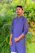 Smiling young man wearing a bright cotton kurta, standing outdoors with a sunny background.