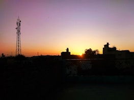 Wide shot of a city skyline with communication towers at sunset.
