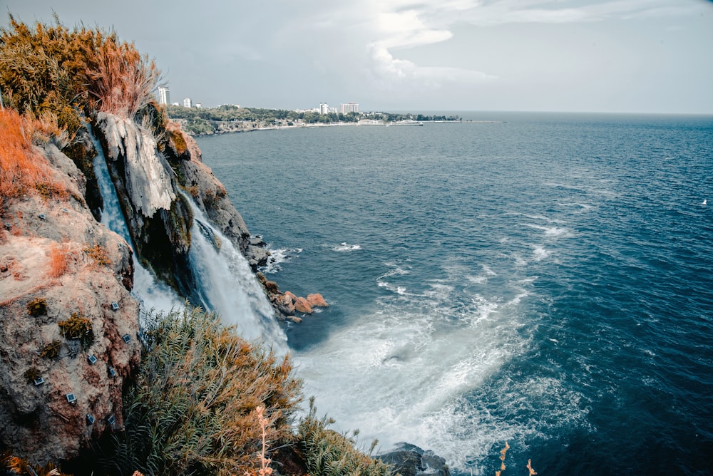 body of water near mountain under white clouds during daytime